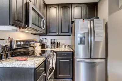 a kitchen with black cabinets and a stainless steel refrigerator at Denver Townhome in Highlands with Spacious Yard! in Denver