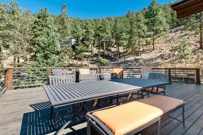 a patio with a table and chairs on a deck at Moose Den Luxury Vacation Home at Windcliff home in Estes Park
