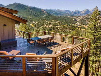 a deck with a table and chairs and mountains at Moose Den Luxury Vacation Home at Windcliff home in Estes Park