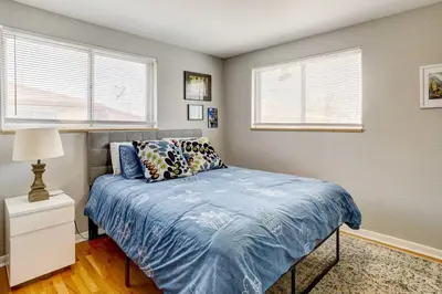 a bedroom with a bed with blue sheets and two windows at Denver Vacation Rental about 3 Mi to Downtown! in Denver