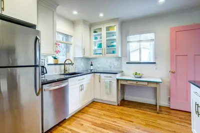 a kitchen with white cabinets and a pink door at Near Denver Zoo Home with Furnished Patio! in Denver