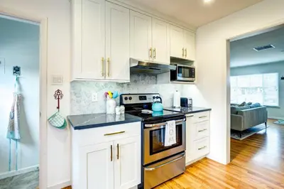 a kitchen with white cabinets and a stove top oven at Near Denver Zoo Home with Furnished Patio! in Denver