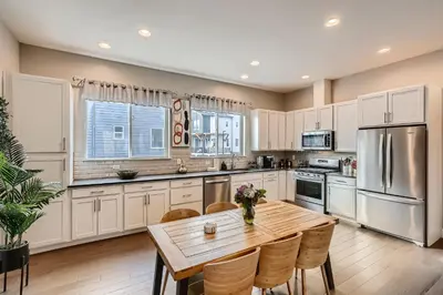 a kitchen with white cabinets and a wooden table at Stylish & Spacious Centrally-Located Home w/Garage in Wheat Ridge