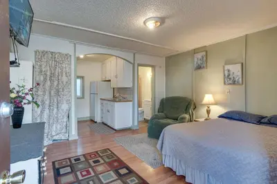 a bedroom with a bed and a chair and a kitchen at Pet-Friendly Loveland Studio Near Boyd Lake! in Loveland