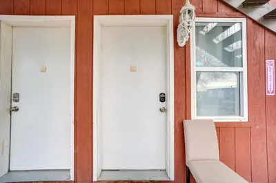 two white doors on a red house with a chair at Loveland Vacation Rental Near Downtown! in Loveland