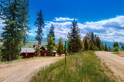 a dirt road next to a red barn and trees at Rainbow Connection in Tabernash