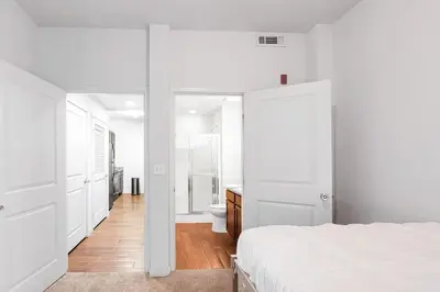 a white bedroom with a bed and a bathroom at Private 2Bdrm Apartment Convenient to All in Greeley