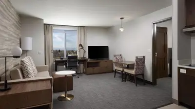 a living room with a table and a desk with a television at Residence Inn by Marriott Denver Aurora in Aurora