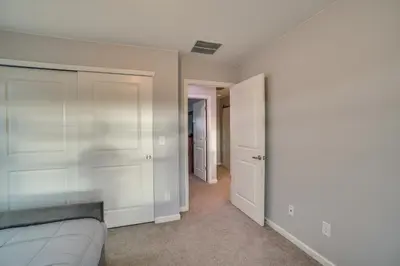 a bedroom with a bed and a hallway with white walls at Fire Pit and Shuffleboard Suburban Denver Home in Denver