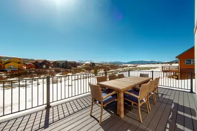 a wooden table and chairs on a deck with a view at Sakura House in Tabernash
