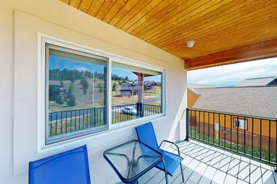 a balcony with two blue chairs and two windows at Sakura House in Tabernash