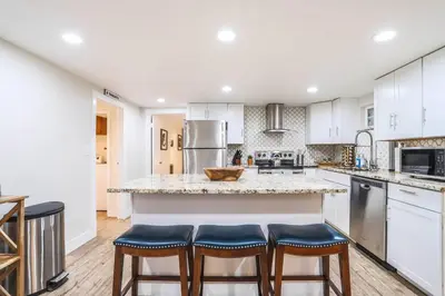 a kitchen with white cabinets and a large island with bar stools at Large Gorgeous House * Patio w/ Outdoor Dining in Denver