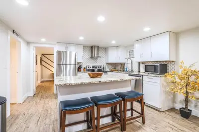 a kitchen with white cabinets and a counter with stools at Large Gorgeous House * Patio w/ Outdoor Dining in Denver