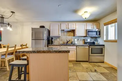 a kitchen with wooden cabinets and a counter top at Winter Park Condo Rental about 2 Mi to Ski Resort! in Winter Park
