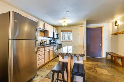 a kitchen with a stainless steel refrigerator and a table at Winter Park Condo Rental about 2 Mi to Ski Resort! in Winter Park