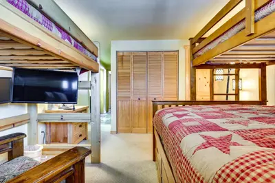 a bedroom with two bunk beds and a flat screen tv at Winter Park Condo Rental about 2 Mi to Ski Resort! in Winter Park