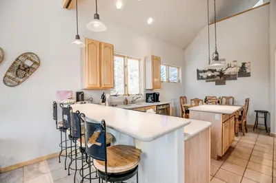 a kitchen with wooden cabinets and a bar with stools at Windflower Retreat: Beautiful Dog Friendly Home in Frisco