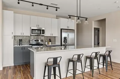 a kitchen with white cabinets and bar stools at Kasa Rino Denver in Denver
