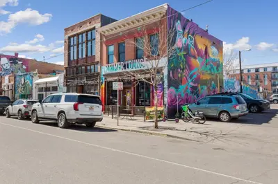 a street with cars parked in front of a building with graffiti at Kasa Rino Denver in Denver