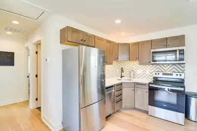 a kitchen with stainless steel appliances and wooden cabinets at Modern Erie Home - Walk to Downtown! in Erie