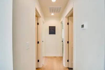 an empty hallway with white walls and wooden floors at Modern Erie Home - Walk to Downtown! in Erie