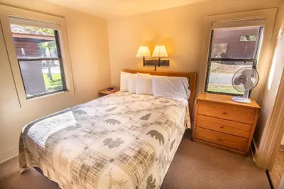 a bedroom with a bed and two windows at Castle Mountain Lodge in Estes Park