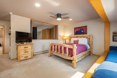 a bedroom with a wooden bed and a television at 2056 The Pines condo in Keystone