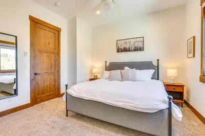 a bedroom with a large bed and a wooden door at Modern Fraser Townhome with Private Hot Tub and Decks! in Fraser