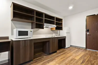 a kitchen with brown cabinets and a white microwave at WoodSpring Suites Fort Collins in Fort Collins