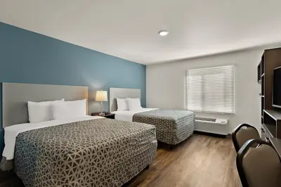 a hotel room with two beds and a window at WoodSpring Suites Fort Collins in Fort Collins