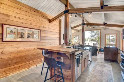 a kitchen with wooden walls and a counter with a island at Hot Tub and Mtn Views Waterfront Grand Lake Cabin! in Grand Lake