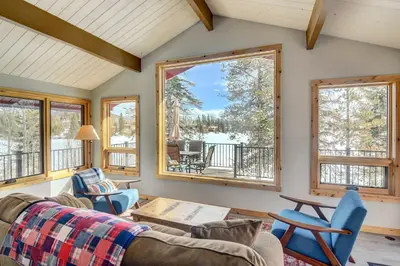 a living room with a couch and two windows at Hot Tub and Mtn Views Waterfront Grand Lake Cabin! in Grand Lake