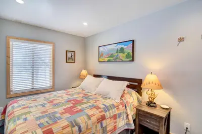 a bedroom with a bed and a lamp and a window at Hot Tub and Mtn Views Waterfront Grand Lake Cabin! in Grand Lake
