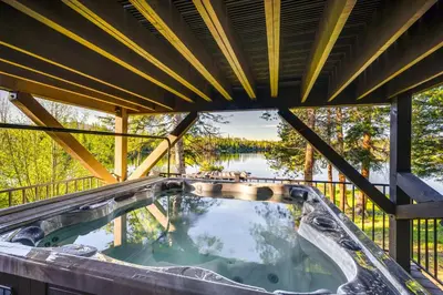 a hot tub on a deck with a view of a lake at Hot Tub and Mtn Views Waterfront Grand Lake Cabin! in Grand Lake