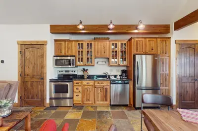 a kitchen with wooden cabinets and stainless steel appliances at Cozy Cabin Retreat in Grand Lake