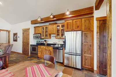 a kitchen with wooden cabinets and a stainless steel refrigerator at Cozy Cabin Retreat in Grand Lake