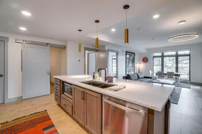 a kitchen with a sink and a living room at Modern Winter Park Condo with Community Hot Tub! in Winter Park
