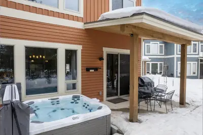 a hot tub on the patio of a house in the snow at Mountain Haus home in Fraser