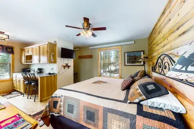 a bedroom with a large bed and a kitchen at Wapiti Point in Grand Lake