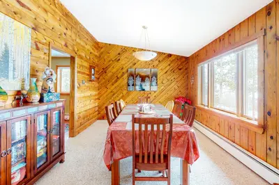 a dining room with a table and chairs and wooden walls at Wapiti Point in Grand Lake