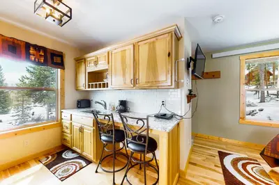 a kitchen with wooden cabinets and a counter with stools at Wapiti Point in Grand Lake