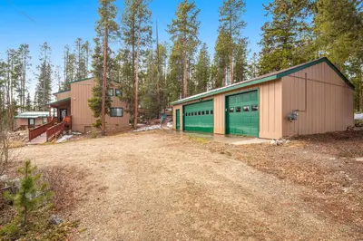a building with green garage doors next to a dirt road at Wapiti Point in Grand Lake