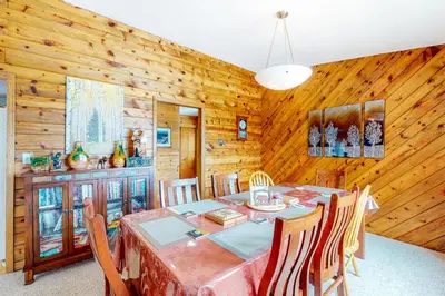a dining room with a table and wooden walls at Wapiti Point in Grand Lake