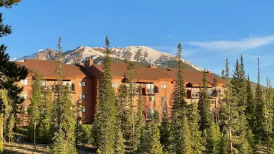 a building surrounded by trees with a mountain in the background at Mountain view, kids room, great location! in Silverthorne