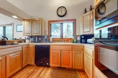 a kitchen with wooden cabinets and a clock on the wall at Elk Trail Retreat in Winter Park