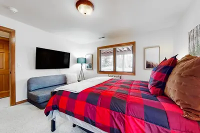 a bedroom with a red and blue bed and a couch at Elk Trail Retreat in Winter Park