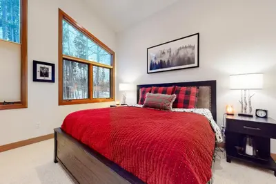 a bedroom with a red bed and two windows at Elk Trail Retreat in Winter Park