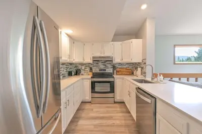 a kitchen with white cabinets and a stainless steel refrigerator at Windwood Alpine Townhome: Downtown Frisco in Frisco