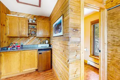 a kitchen with wooden cabinets and a wall with a window at Wapiti Point - Main House in Grand Lake