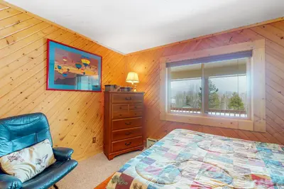 a bedroom with a bed and a dresser and a window at Wapiti Point - Main House in Grand Lake